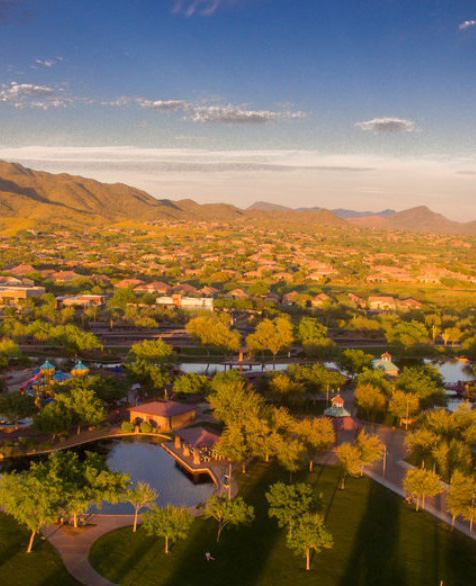 Aerial view of Anthem, Arizona, showcasing residential neighborhoods, lush greenery, and scenic mountains, emphasizing the community's family-friendly environment and outdoor spaces.