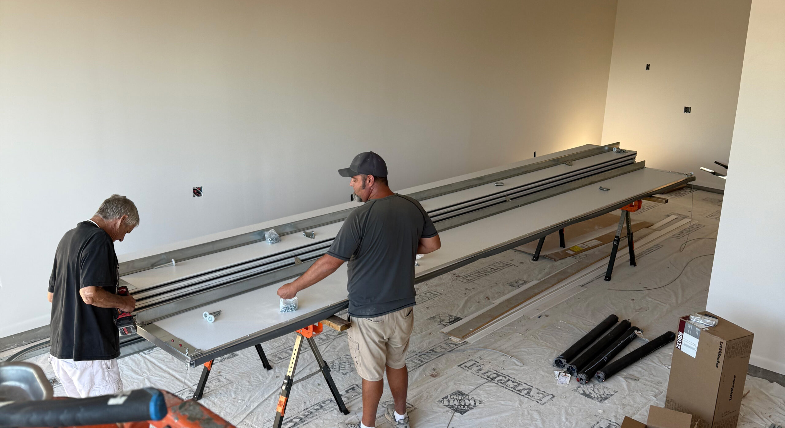 Two technicians assembling garage door components in a workspace, highlighting the installation process for AZ Garage Door Pros LLC services.