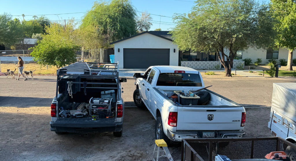 White pickup truck and work van parked in front of residential property, showcasing tools and equipment for garage door repair services in New River, Arizona.