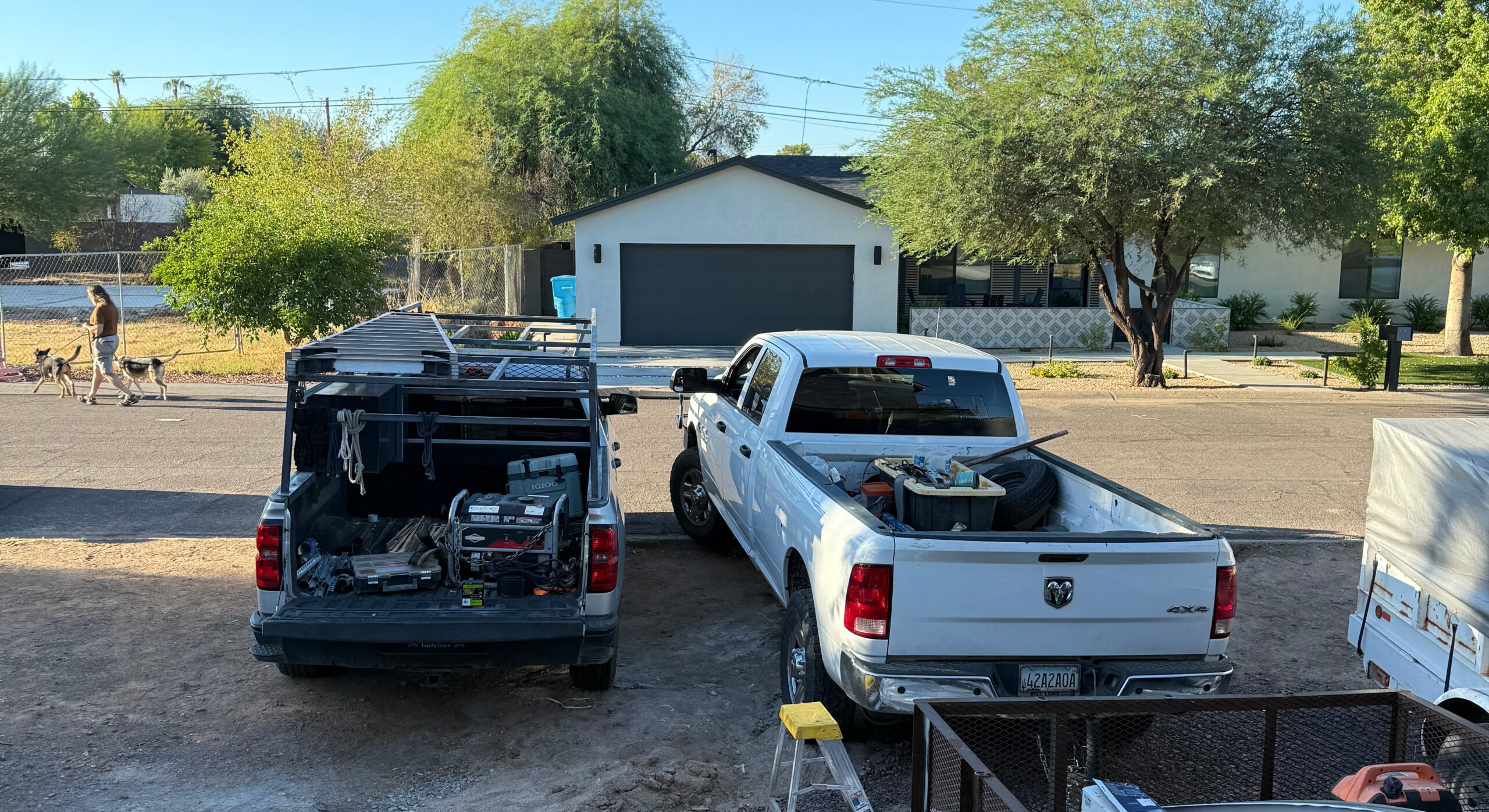 White pickup truck parked next to a service vehicle, with a garage door in the background, and a person walking two dogs nearby, representing the garage door service context.