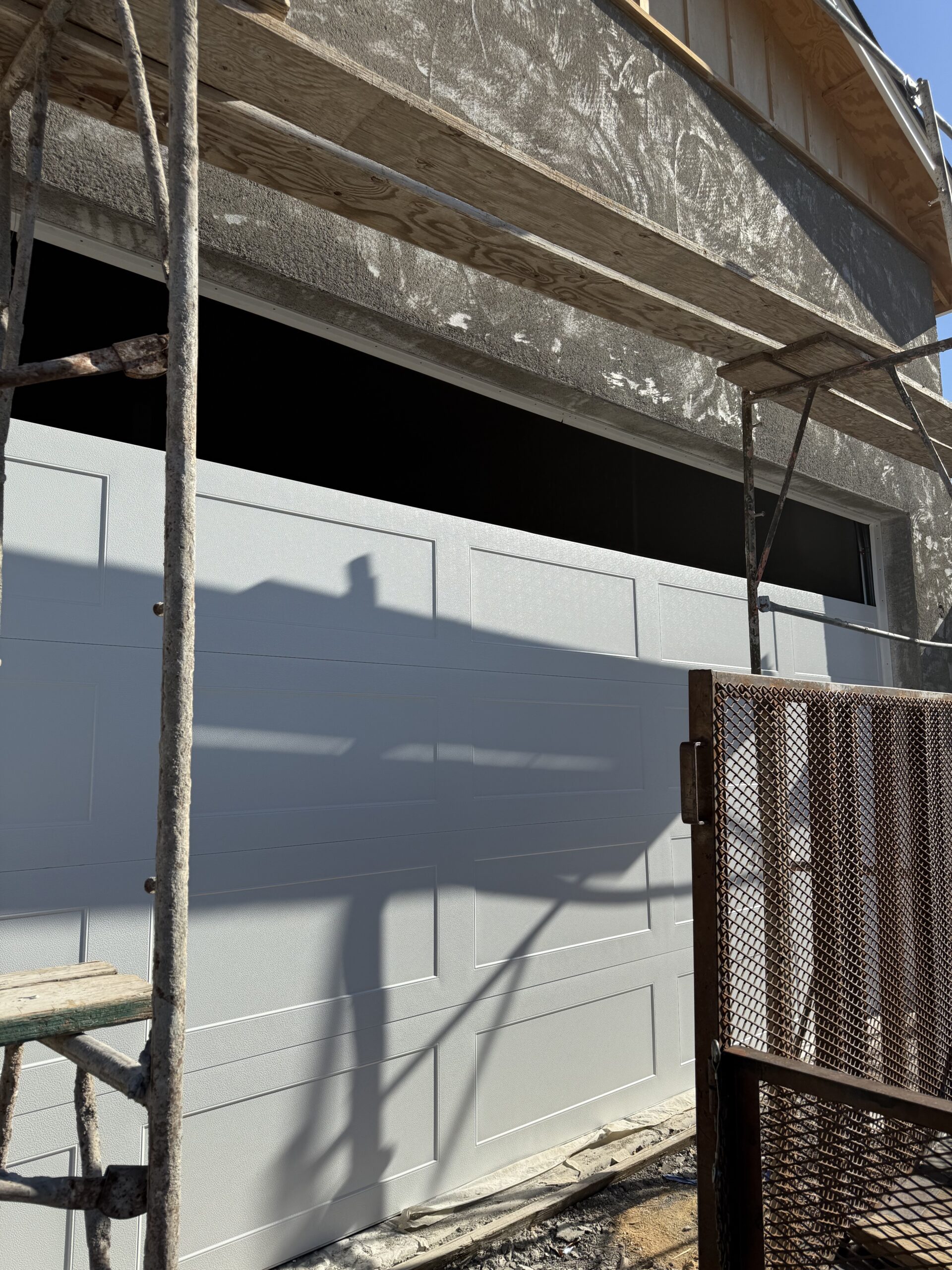 Garage door installation in progress, showcasing a new white garage door with scaffolding and construction materials, emphasizing AZ Garage Door Pros LLC's commitment to quality workmanship.