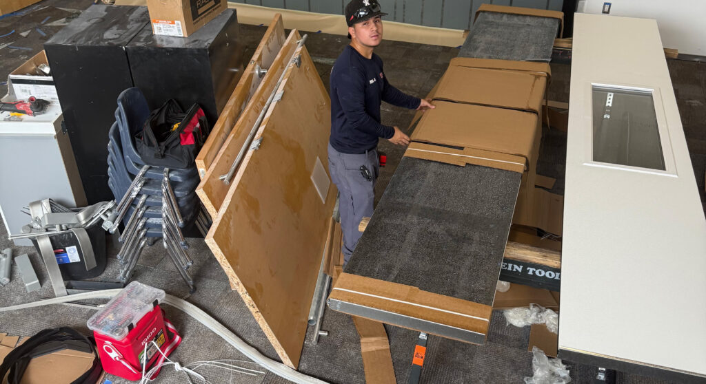 Person assembling garage door opener components in a workshop, surrounded by tools and materials, illustrating the installation process for AZ Garage Door Pros LLC services.