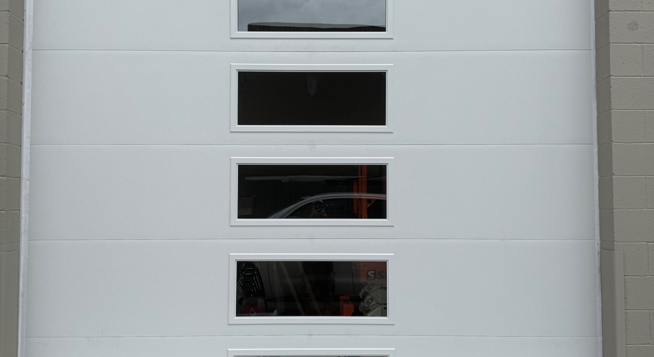 New garage door installation featuring multiple windows, emphasizing safety and reliability for residential and commercial properties.
