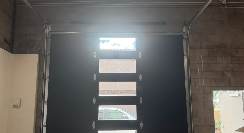 Garage door with windows, partially open, inside a garage setting, highlighting repair services by AZ Garage Door Pros LLC.