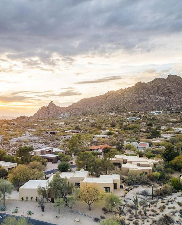 Desert landscape with residential homes nestled among rocky hills and cacti at sunset, reflecting the North Phoenix area's natural beauty.