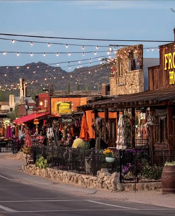 Cozy outdoor dining scene at restaurants in Cave Creek, Arizona, featuring string lights, colorful umbrellas, and desert landscape backdrop.