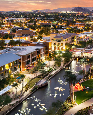 Scenic view of Scottsdale, Arizona at dusk, showcasing well-maintained homes, upscale neighborhoods, and decorative water features along a canal, highlighting the importance of aesthetics and property standards in the area.